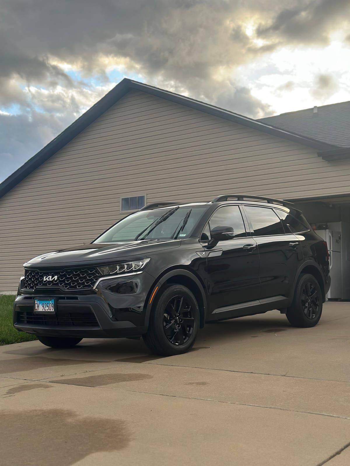 Black Kia Sorento with glossy paint under a dramatic sky after mobile detailing