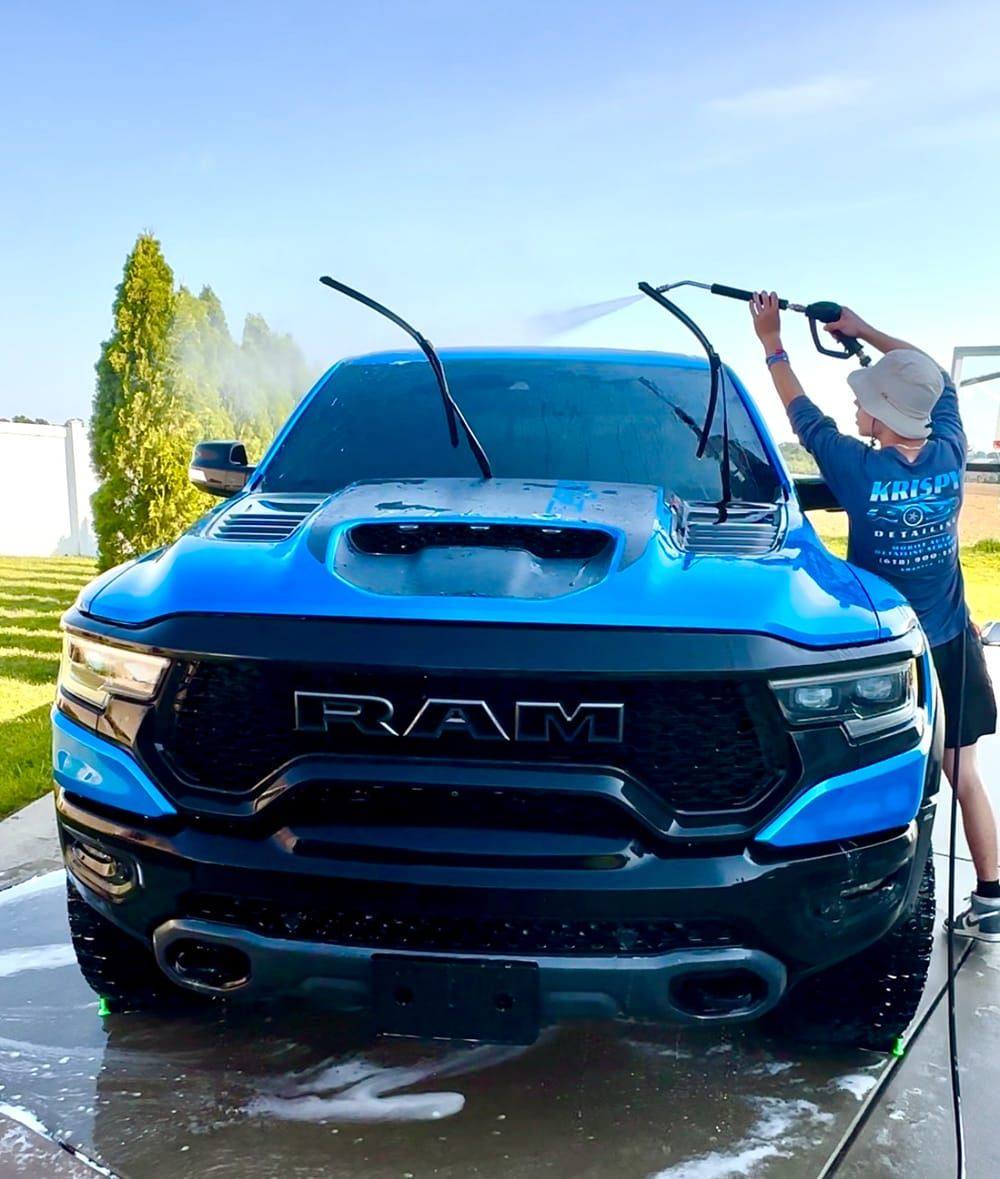 Polished Midwest owner pressure-washing a blue Ram TRX during a mobile detail